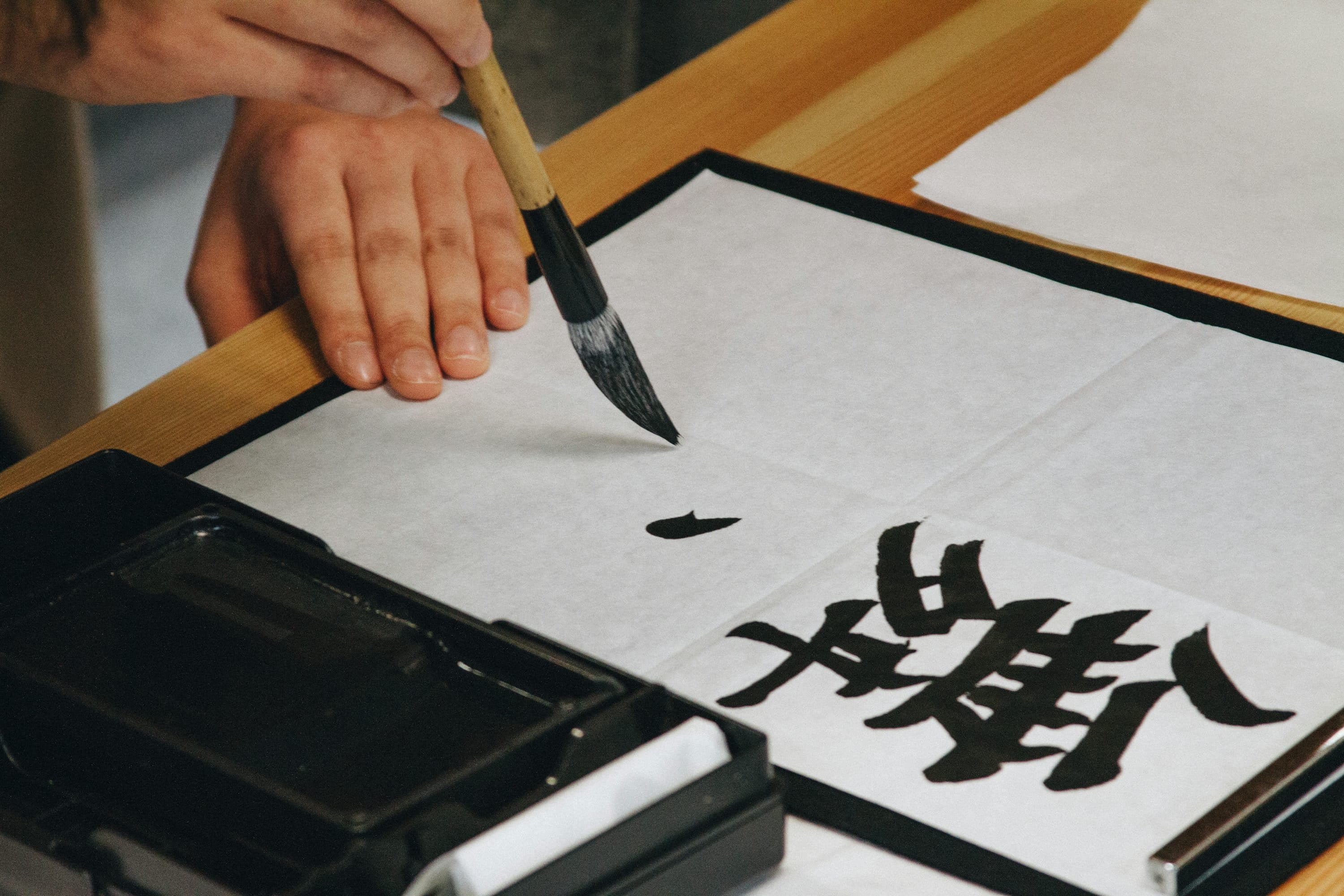 Japanese calligraphy brush creating a bold, flowing stroke in black ink